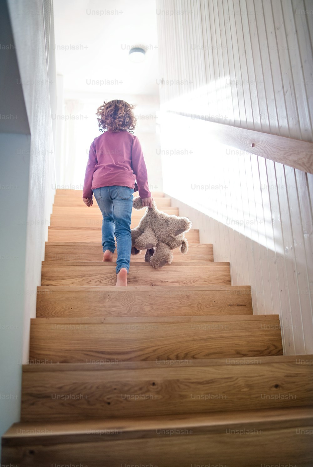 自宅の室内で木製の階段を上る小さな女の子の後ろ姿。スペースをコピーします。