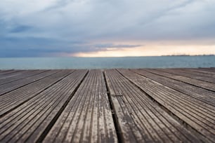 A view of wooden decking, sea and gray sky at dusk.