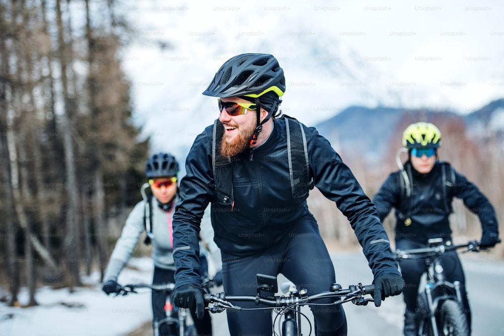 겨울에 야외 도로를 달리는 젊은 산악 자전거 타는 사람들의 정면보기.