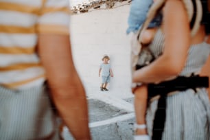 A midsection of family with two toddler children in town on summer holiday.