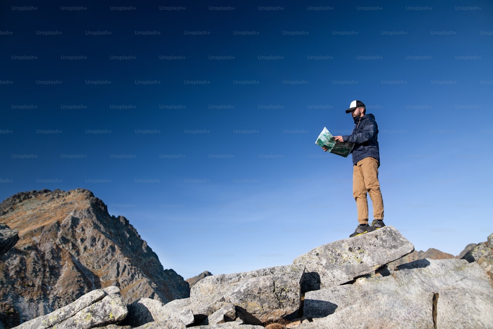 Mature man hiking in mountains in summer, using map. Copy space.
