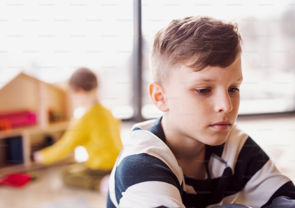 A portrait of small boy sitting on the floor at home. Copy space.