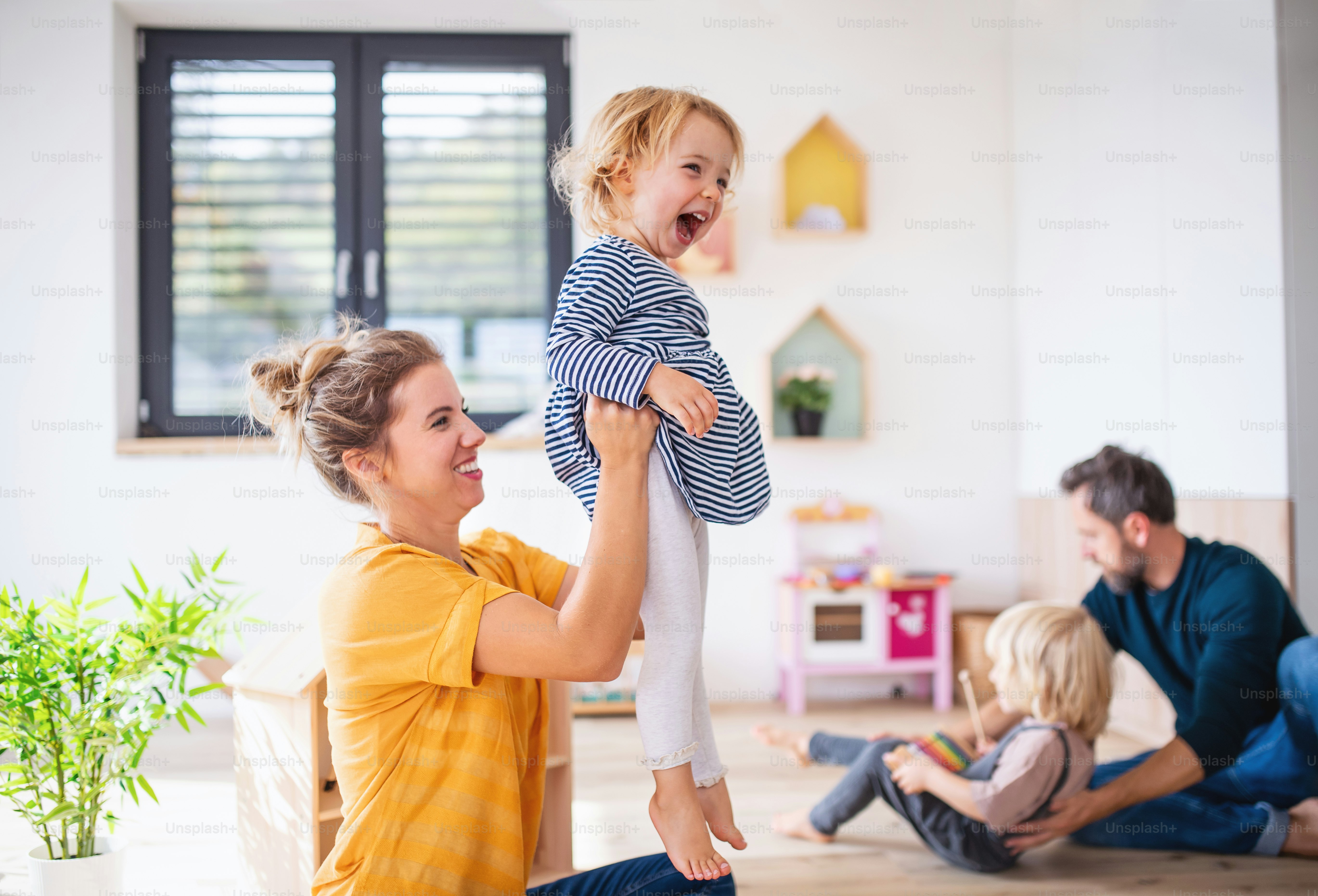 Junge Familie mit zwei kleinen Kindern drinnen im Schlafzimmer, Spaß haben.
