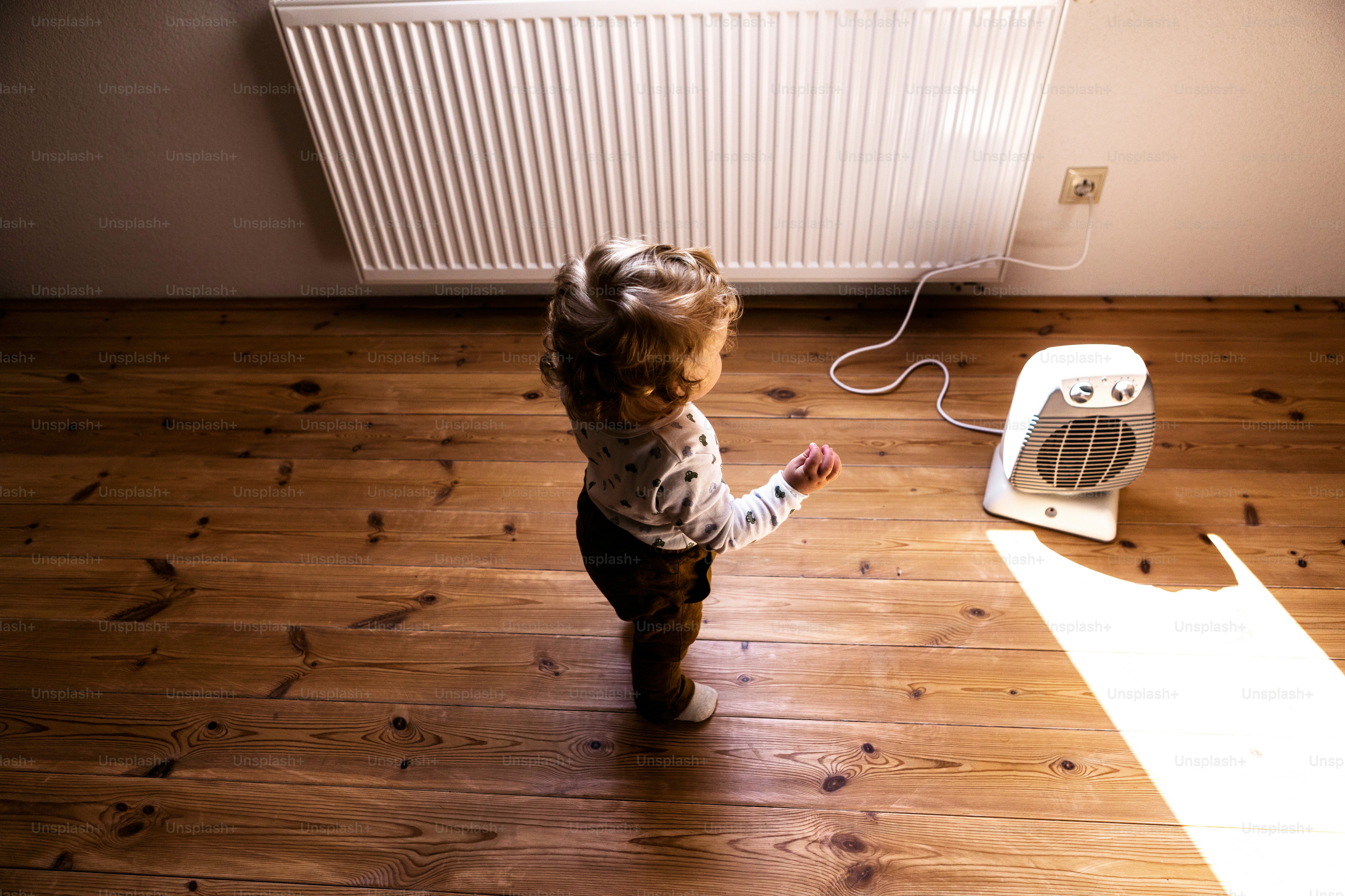 Cute little boy at home standing at the fan in bedroom.