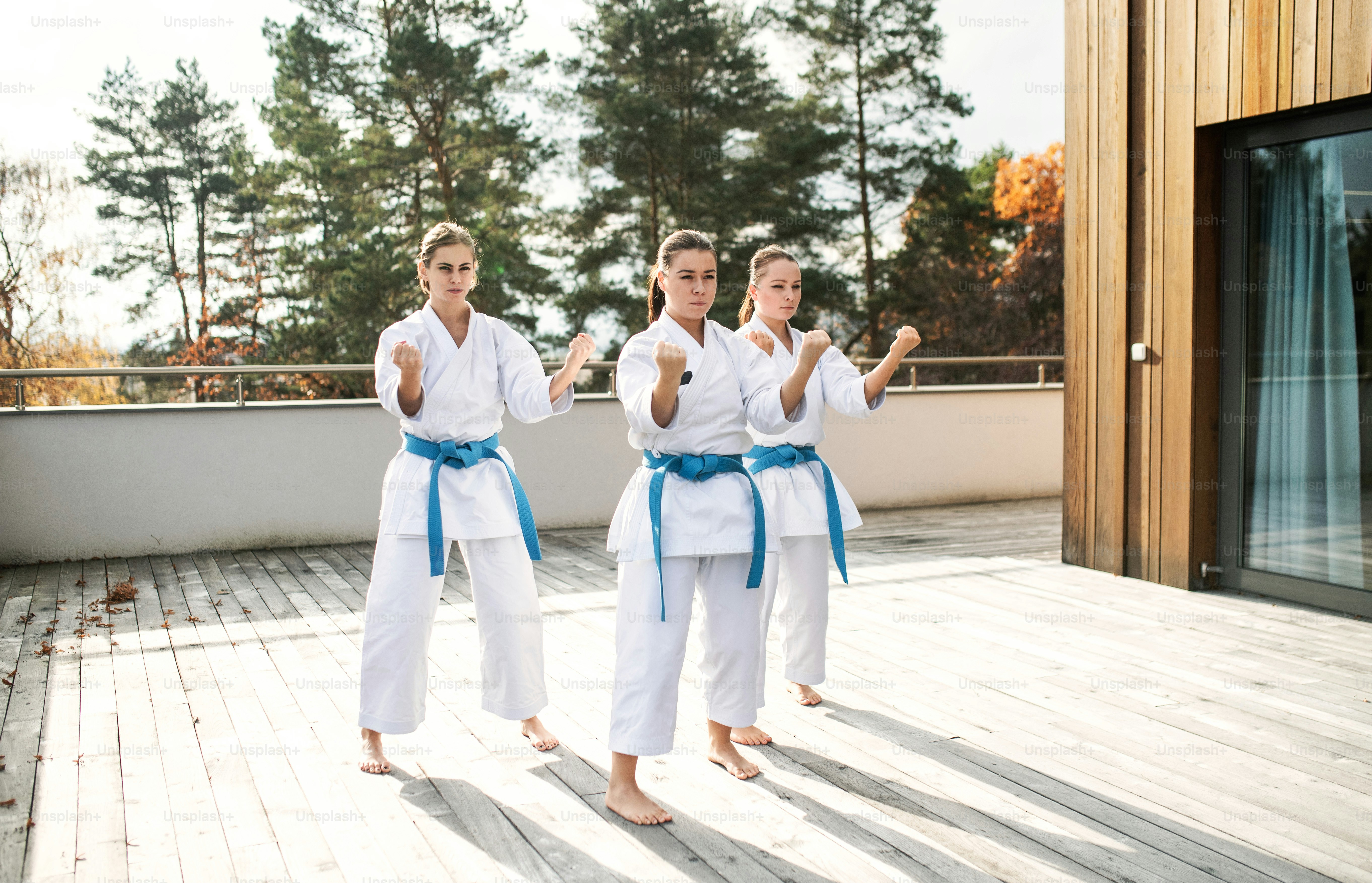 Un grupo de mujeres jóvenes practicando karate al aire libre en una terraza