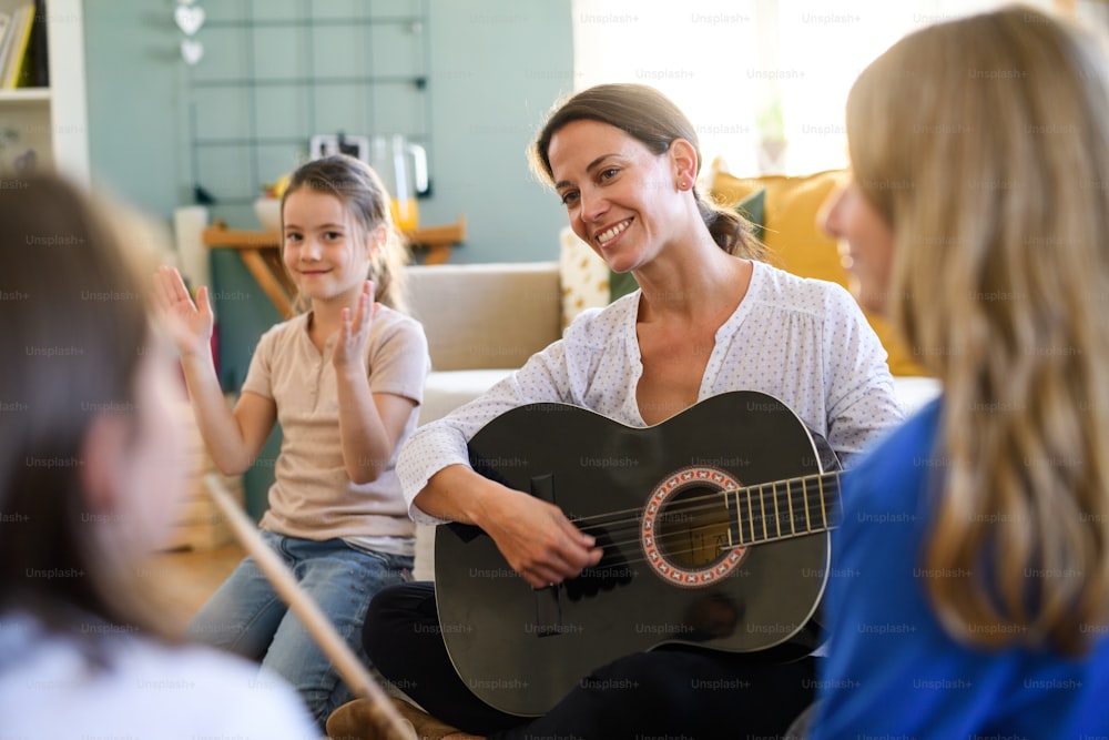 Groupe d’enfants joyeux faisant l’école à la maison avec un enseignant ayant une leçon de musique à l’intérieur, concept de coronavirus.