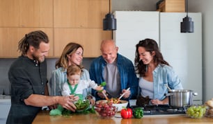 Happy multigeneration family indoors at home preparing vegetable salad in kitchen.