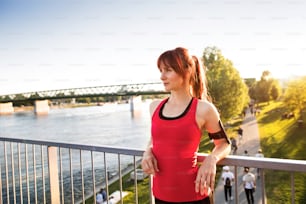 Beautiful fit young runner in the city at the river resting.