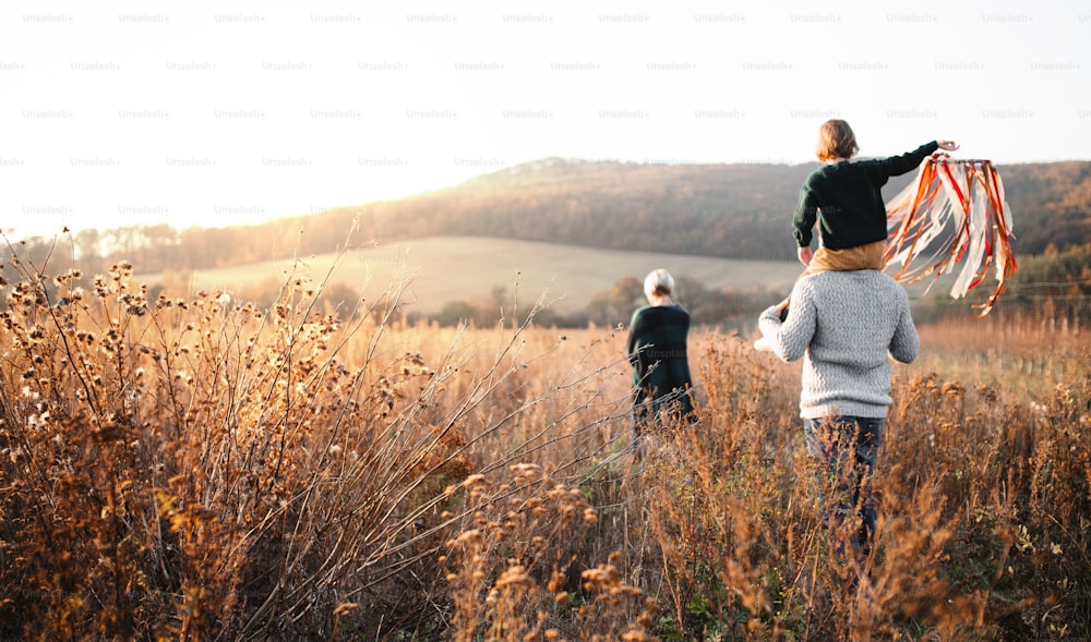 Vue arrière d’une famille avec une petite fille lors d’une promenade dans la nature d’automne, à pied.