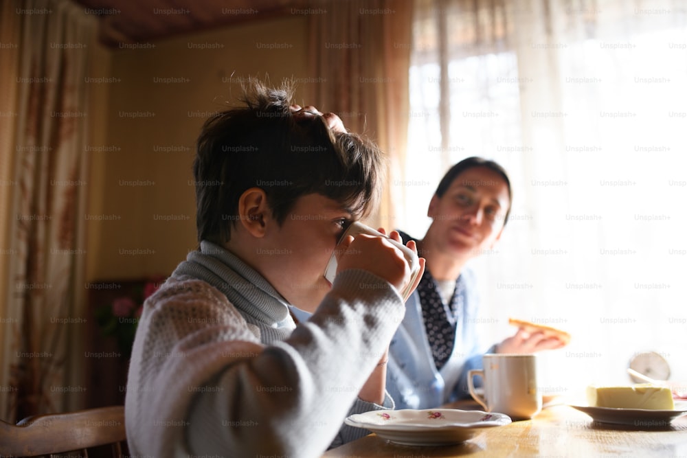 Un retrato de una niña pobre con la madre comiendo en el interior de la casa, concepto de pobreza.