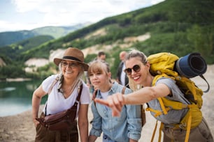 A happy multigeneration family on hiking trip on summer holiday, pointing at something.