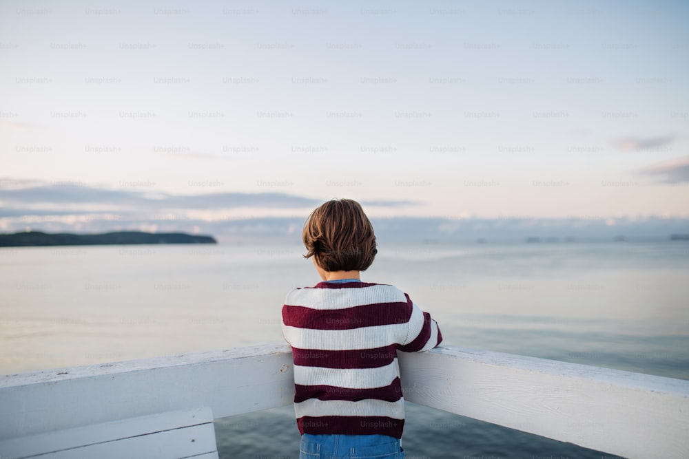 Eine Rückansicht des jugendlichen Mädchens mit Blick auf den Blick ins Freie am Pier am Meer, Urlaubskonzept.