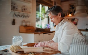 Una anciana haciendo pasteles en la cocina de su casa. Espacio de copia.