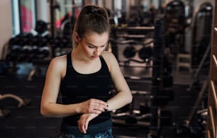 Niña o mujer joven haciendo ejercicio en un gimnasio, usando un reloj inteligente.