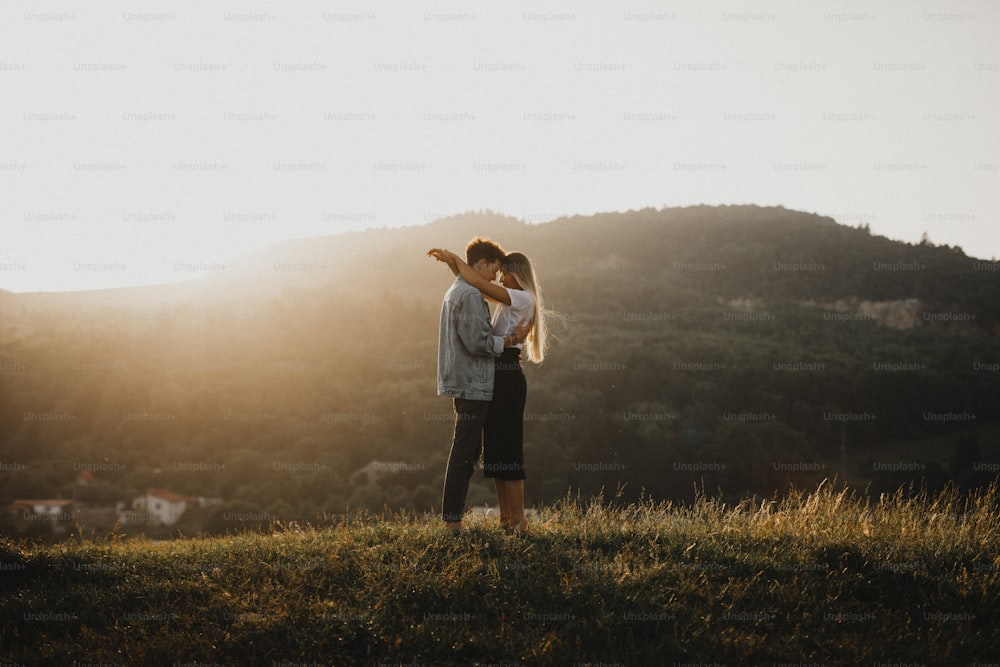 Vista laterale di giovane coppia su una passeggiata nella natura al tramonto in campagna, abbracciandosi.