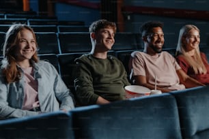 Jovens com pipoca no cinema, assistindo a um filme de suspense.