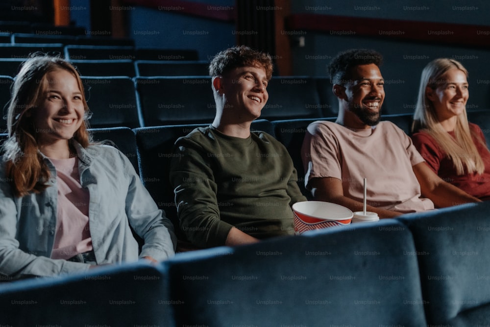 Jóvenes con palomitas de maíz en el cine, viendo una película de suspenso.