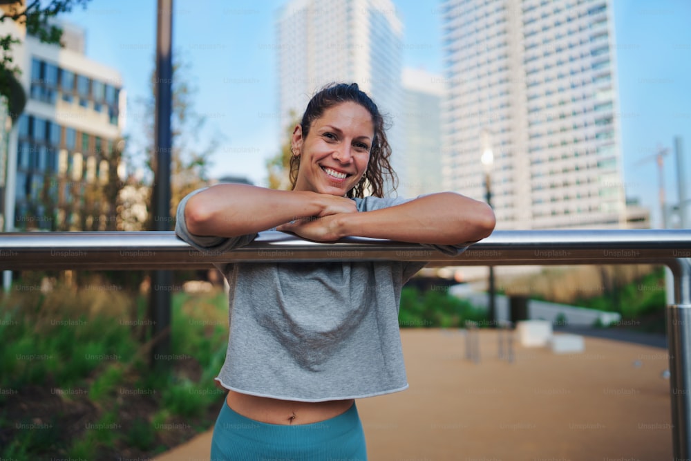 Donna adulta media che fa esercizio su un tappetino all'aperto nel parco di allenamento della città, concetto di stile di vita sano.
