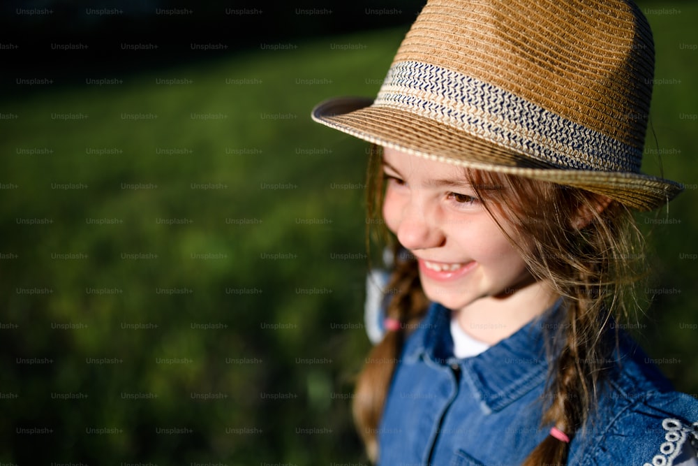 Close-up portrait of small girl standing outdoors in spring nature. Copy space.