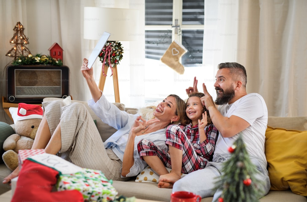 Familie mit kleiner Tochter zu Weihnachten zu Hause, mit Videoanruf auf dem Tablet.