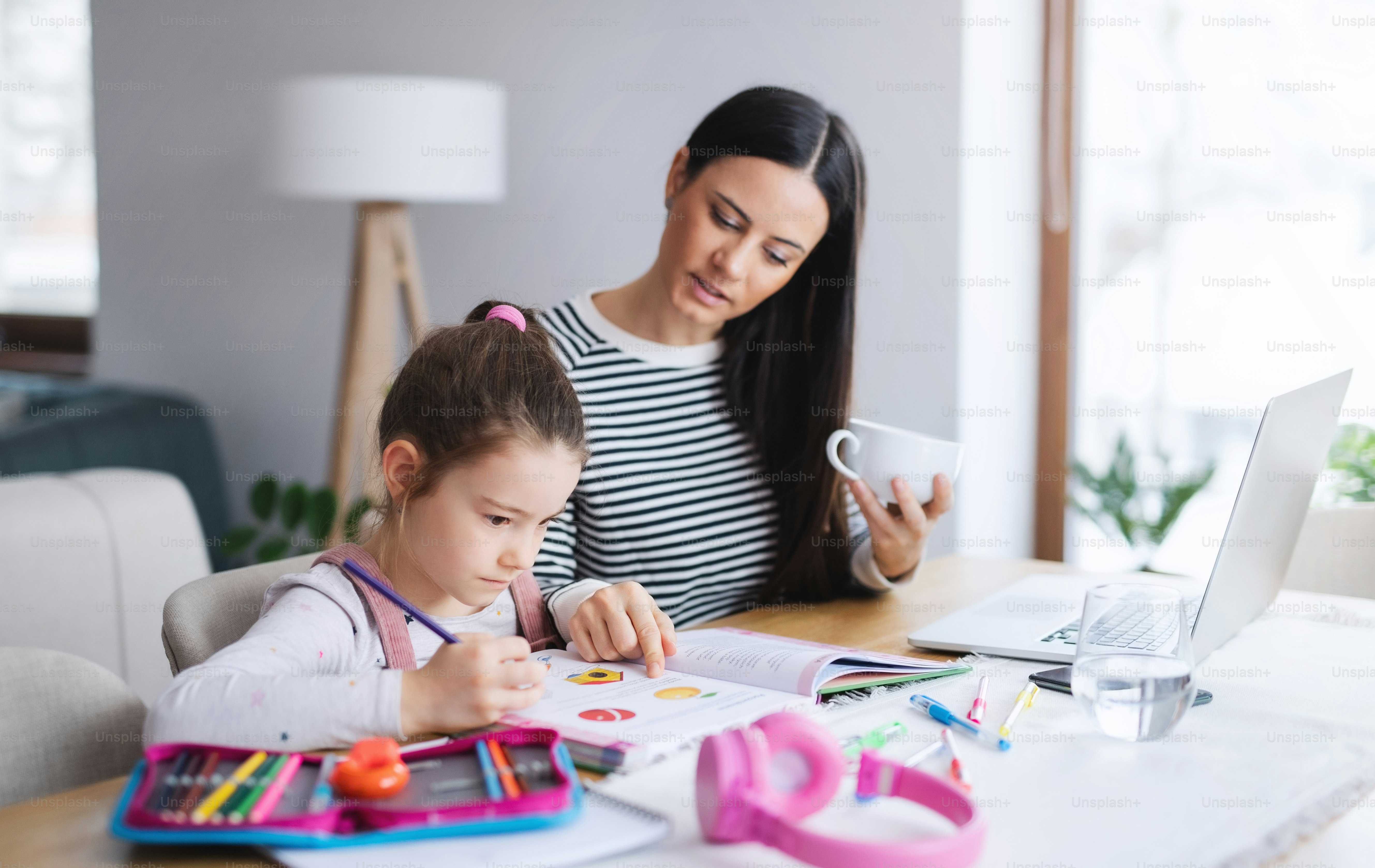 Mother with school girl indoors at home, distance learning and home ...
