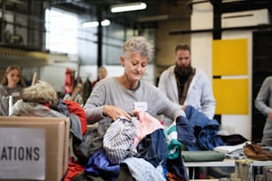 Retrato de voluntarios clasificando la ropa donada en el centro de donaciones de caridad de la comunidad.