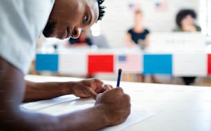 African-american man voter in polling place, usa elections concept, writing.