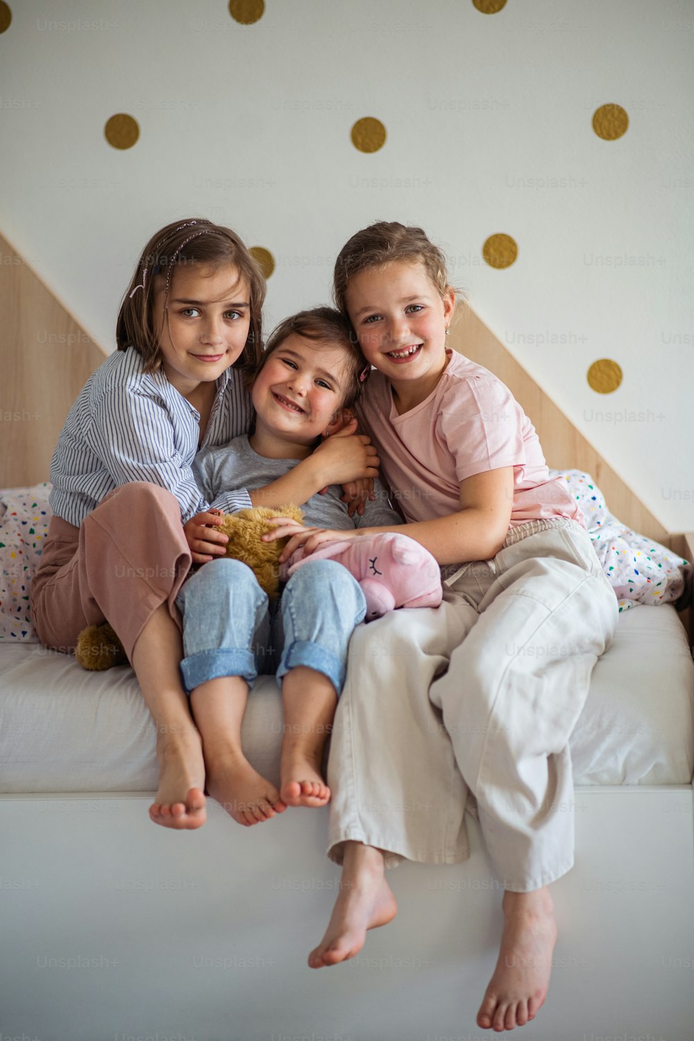 A portrait of three girls sisters indoors at home, looking at camera.
