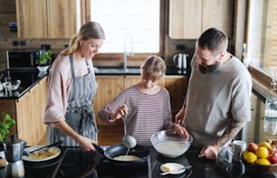 Familia feliz con una hija pequeña cocinando en el interior, vacaciones de invierno en un apartamento privado.
