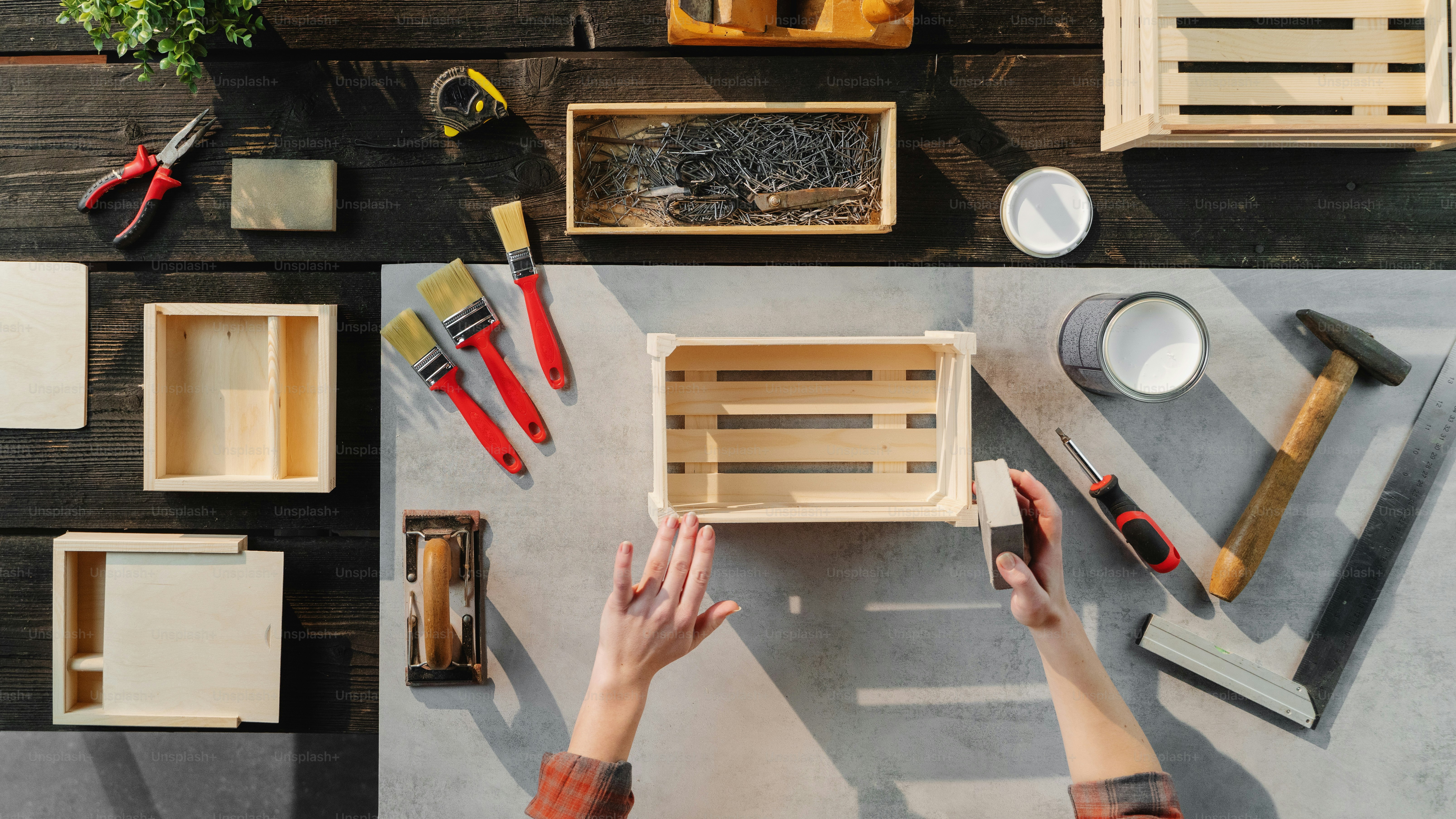 A top view of unrecognizable woman making wooden boxes, small business and desktop concept