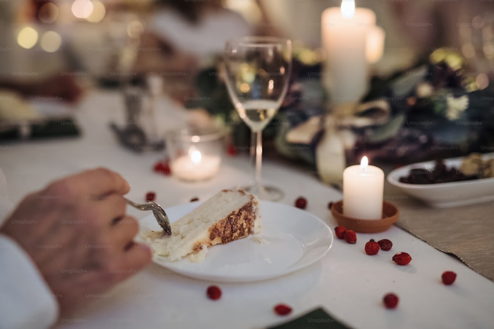Midsection of unrecognizable man indoors at the table at Christmas dinner, eating cake.