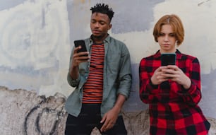 Young biracial couple addicted to smartphones outdoors in a town, social media concept