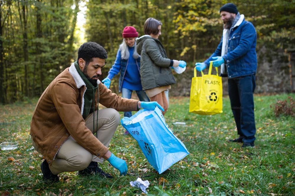 Un gruppo eterogeneo di volontari ripulisce la foresta dai rifiuti, concetto di servizio alla comunità