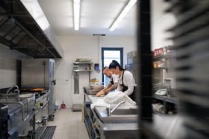 Um chef e cozinheiro trabalhando em seus pratos dentro de casa na cozinha do restaurante.