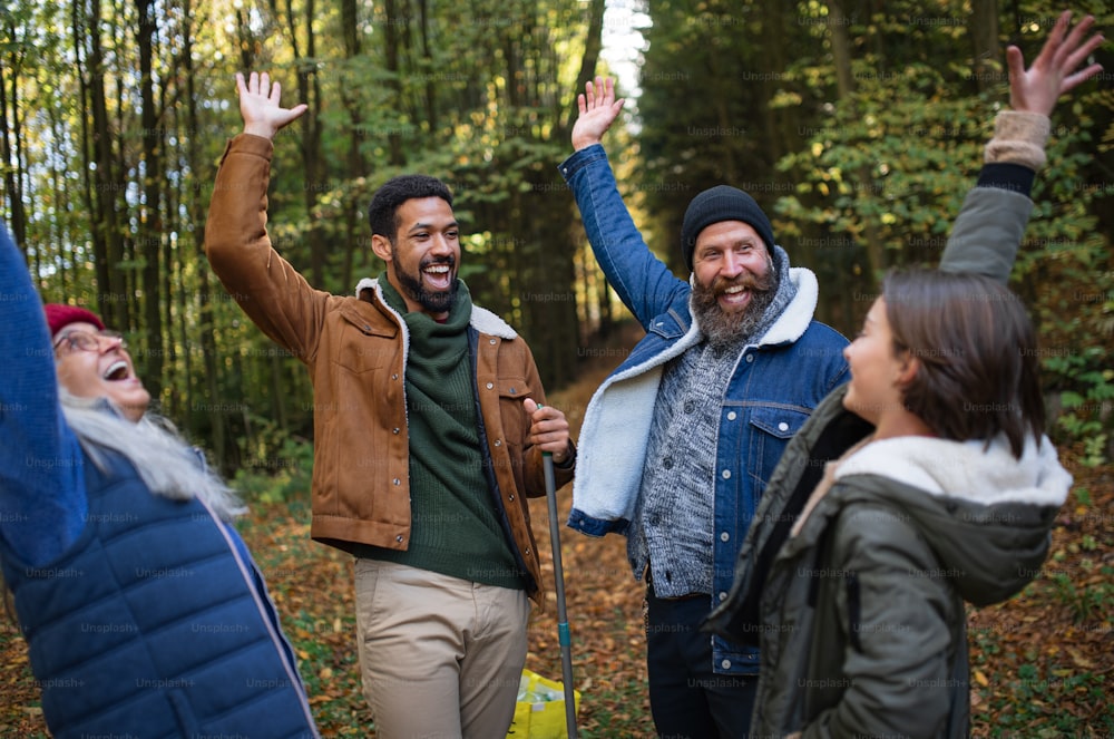 Eine bunt gemischte Gruppe glücklicher Freiwilliger feiert gemeinsam Erfolge nach dem Aufräumen des Waldes.