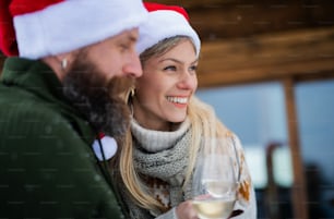 A portrait of happy mature couple in love enjoying holiday in mountain hut, standing outdoors.