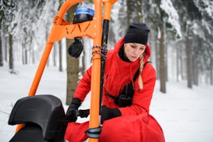 Paramedic woman from mountain rescue service provide an operation outdoors in winter in forest.