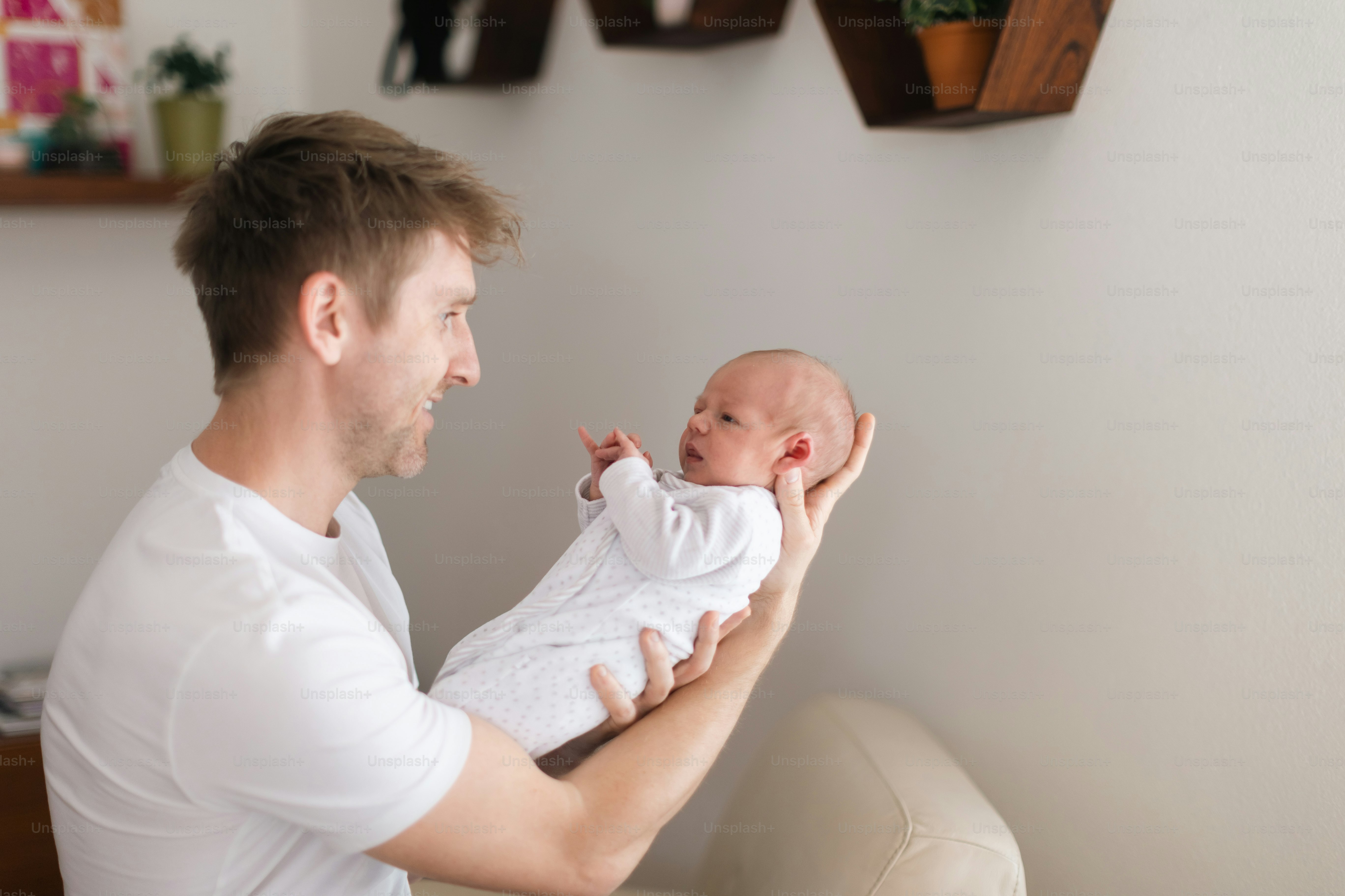 Ein Vater, der seinen neugeborenen Sohn zu Hause hält.