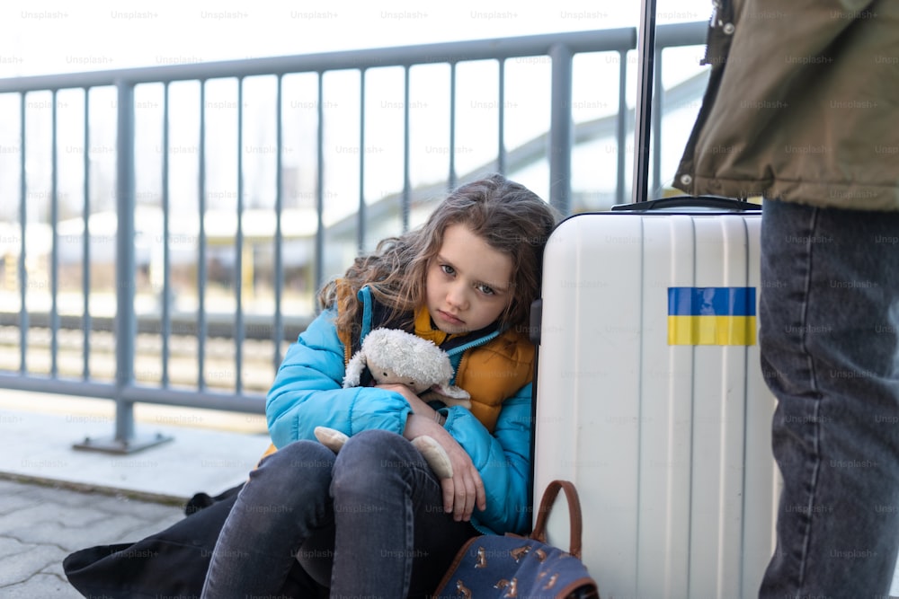 기차역에서 기다리는 짐을 가진 슬픈 우크라이나 이민자 아이, 우크라이나 전쟁 개념.