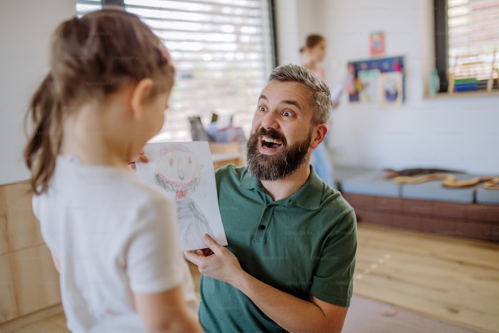 A happy father getting drawings from his little daughter at home.