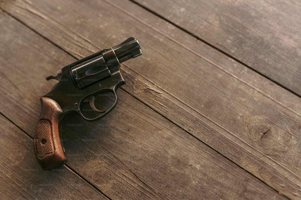 A revolver on the wooden table, copy space.