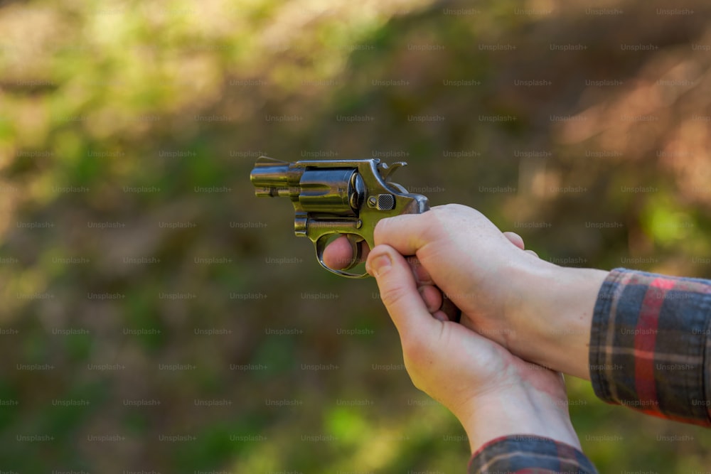 Un homme méconnaissable avec un revolver sur une cible de tir sur un champ de tir en plein air.