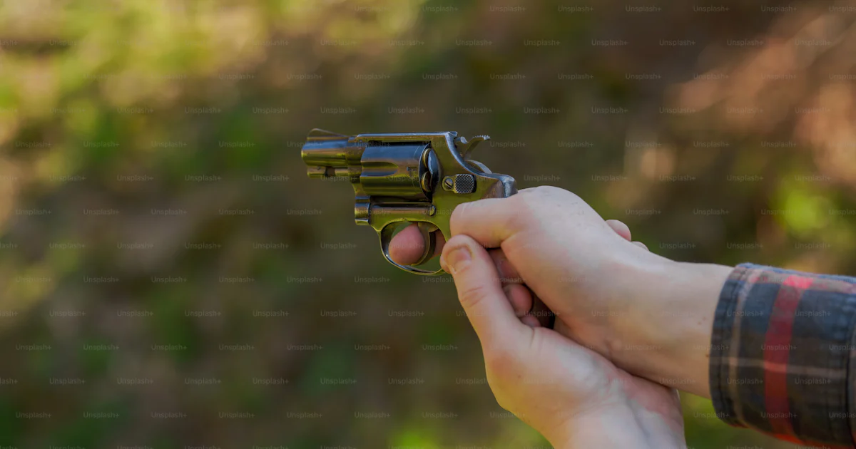 Man With Revolver An unrecognizable man with revolver aiming target on shooting range ...