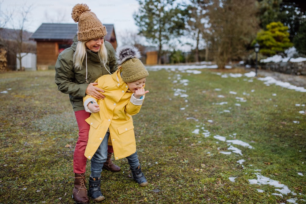 A boy with Down syndrome with his mother playing in garden in winter.