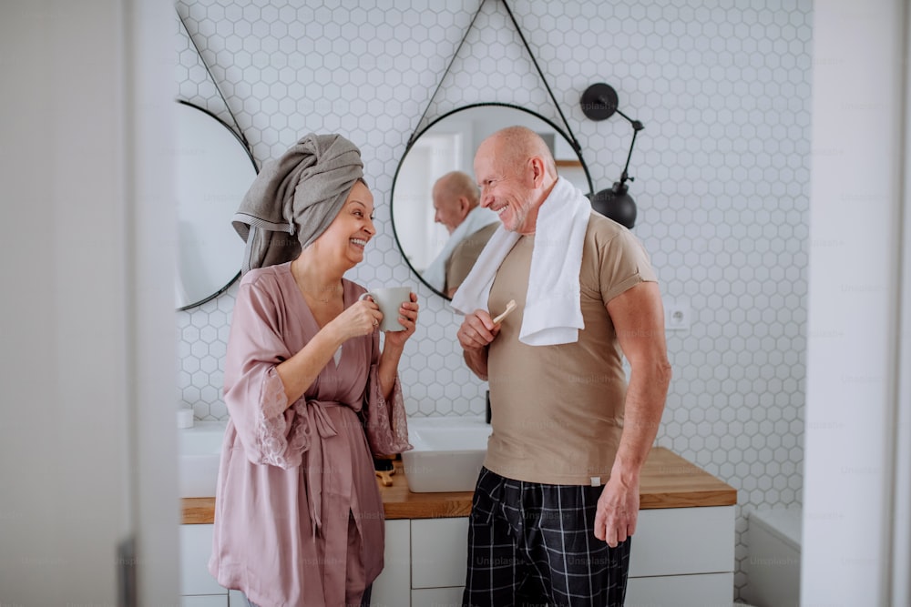 A senior couple in bathroom, brushing teeth and talking, morning routine concept.