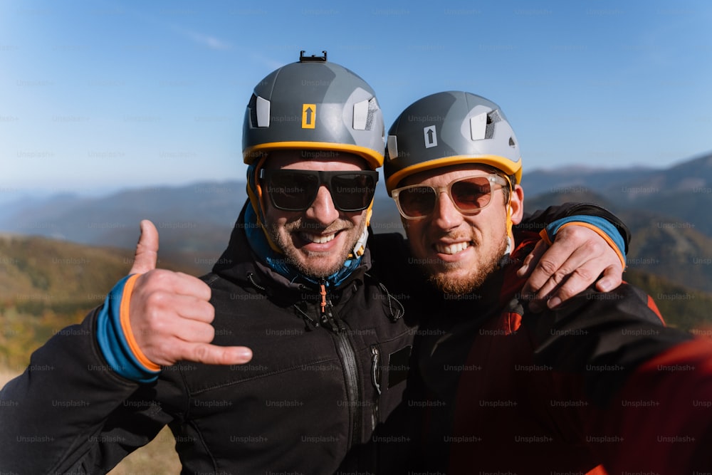 A portrait of two paragliders preparing for the flight on mountain, looking at camera. Extreme sports activity.