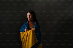 Traurige Frau mit ukrainischer Flagge bedeckt