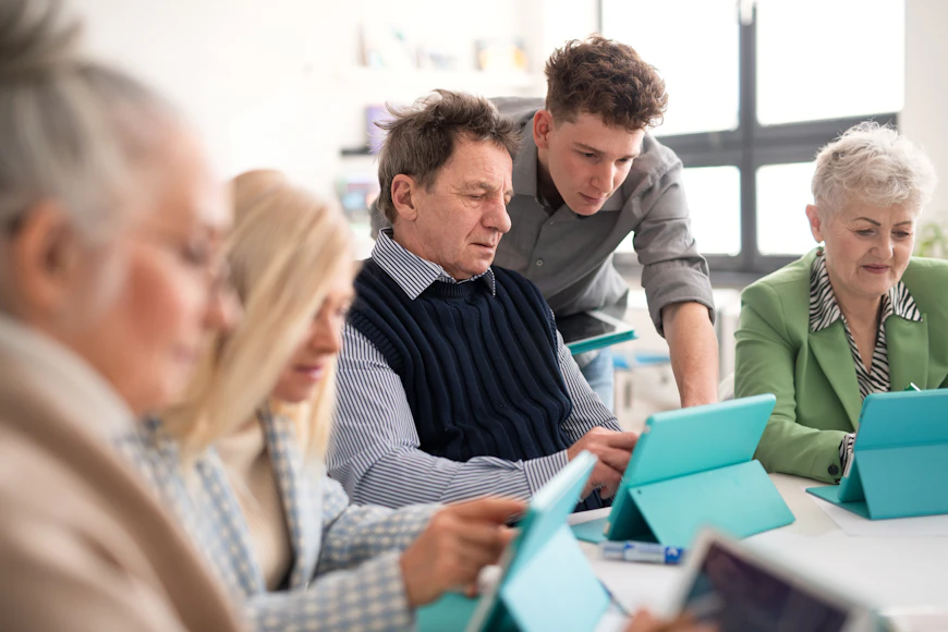 Elderly person being helped with their computer by a family member or technician