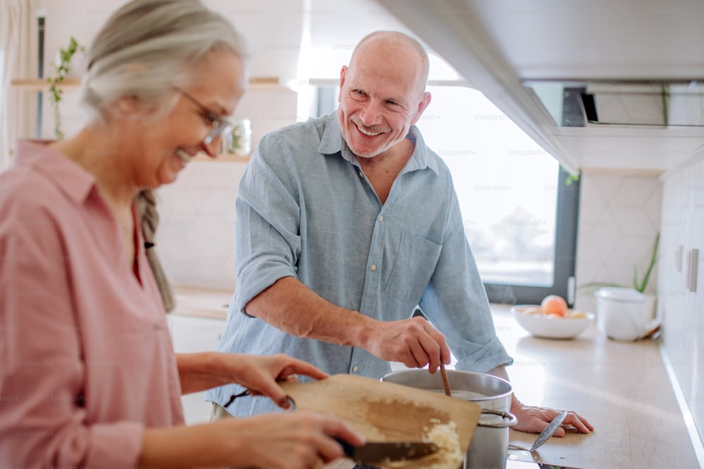 Una pareja de ancianos cocinando juntos en casa.