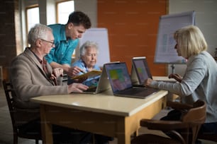 A senior group in retirement home with young instructor learning together in computer class